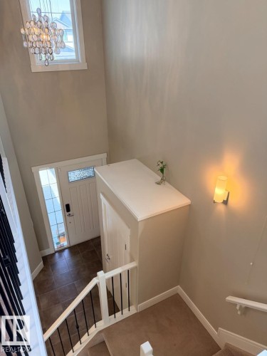 Two-story foyer featuring an ornate chandelier, a white entry door with decorative glass inserts, and a tiled floor - 648 178 Street, Edmonton, AB - Indoor Photo Showing Other Room