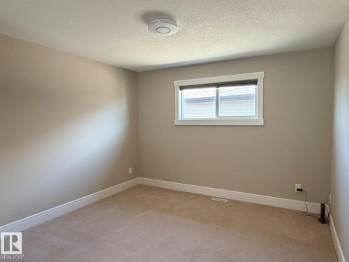 Carpeted room featuring a white-framed window with blinds, neutral wall paint, white baseboards, and a ceiling-mounted smoke detector - 648 178 Street, Edmonton, AB - Indoor Photo Showing Other Room
