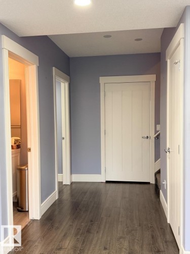 Hallway featuring wood-finish flooring, white trim, recessed lighting, and pale blue wall paint - 648 178 Street, Edmonton, AB - Indoor