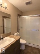 Bathroom featuring a dark wood-finish vanity with a granite-style countertop, an undermount sink, a large mirror, and a shower with frosted sliding glass doors - 