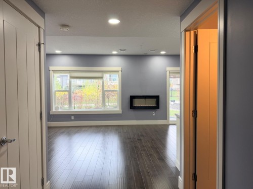 Spacious room featuring wood-finish flooring, a contemporary wall-mounted fireplace, and multiple recessed light fixtures - 648 178 Street, Edmonton, AB - Indoor Photo Showing Other Room