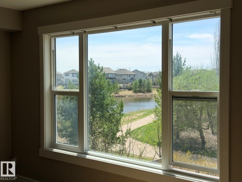 Expansive triple-pane window featuring white trim and a water-body backdrop - 648 178 Street, Edmonton, AB - Indoor Photo Showing Other Room