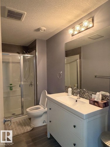 Bathroom featuring a white vanity with integrated sink, chrome faucet, and mosaic tile backsplash - 648 178 Street, Edmonton, AB - Indoor Photo Showing Bathroom