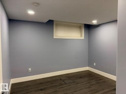 Spacious room featuring wood-finish flooring, light blue wall paint, white baseboards, and recessed ceiling lighting - 