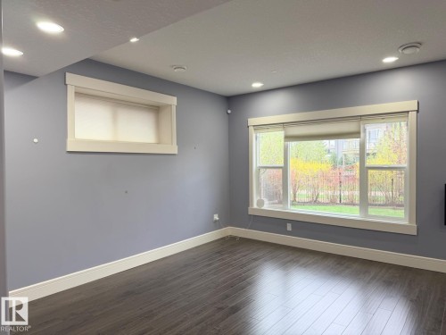 Interior room featuring deep blue-gray walls, dark wood-finish flooring, white baseboards, and white window trim - 648 178 Street, Edmonton, AB - Indoor Photo Showing Other Room