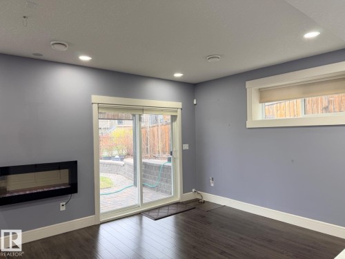 Interior space featuring wood-finish flooring, recessed ceiling lighting, and a wall-mounted linear fireplace - 648 178 Street, Edmonton, AB - Indoor Photo Showing Other Room With Fireplace