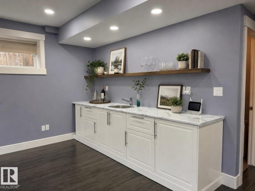 Wet bar featuring white shaker-style cabinetry with brushed nickel hardware, a rectangular undermount sink, and a white marble-look countertop - 648 178 Street, Edmonton, AB - Indoor Photo Showing Other Room