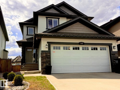 Two-story residence featuring light-colored horizontal siding, dark shake siding accents, and stone veneer detailing - 648 178 Street, Edmonton, AB - Outdoor