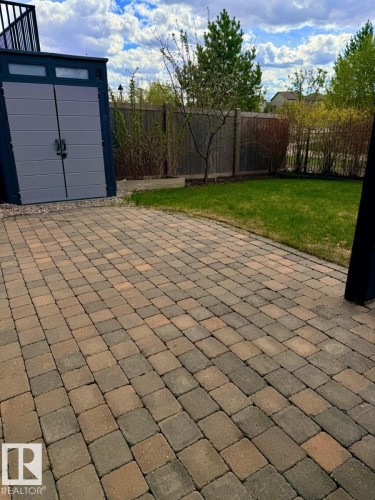 Paver patio with a manicured lawn, surrounded by a wooden privacy fence, and mature landscaping - 648 178 Street, Edmonton, AB - Outdoor