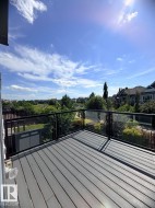 Private elevated deck featuring composite decking and glass panel railings with black metal posts - 