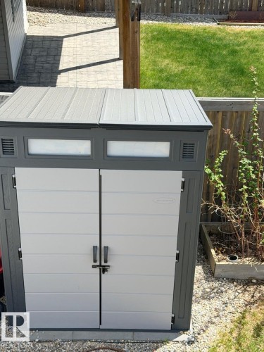 Gray and white outdoor storage shed featuring double doors with handles and a latch, horizontal paneling, and upper transom-style windows - 648 178 Street, Edmonton, AB - Outdoor With Exterior