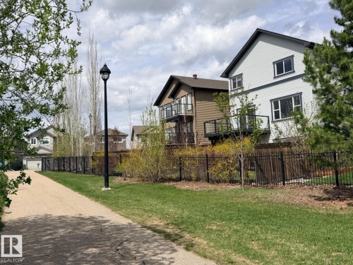 Expansive green space featuring a gravel walking path, mature trees, and a black wrought iron fence - 648 178 Street, Edmonton, AB - Outdoor