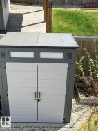 Two-tone outdoor storage shed with double doors, integrated light panels, and a slatted roof design - 