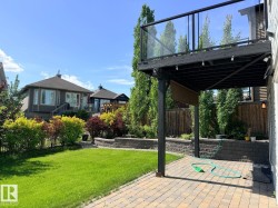 Expansive backyard featuring a manicured lawn, a two-tier retaining wall, and mature landscaping - 