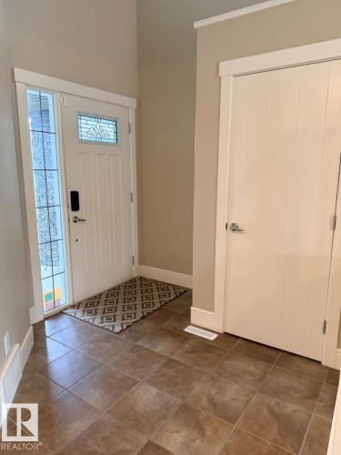Entryway featuring ceramic tile flooring, a white paneled door with leaded glass insert, and a sidelight window - 648 178 Street, Edmonton, AB - Indoor Photo Showing Other Room