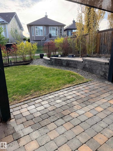 Multi-toned paver patio leading to a manicured lawn area - 648 178 Street, Edmonton, AB 