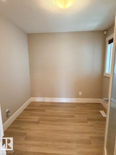Wood-finish flooring with white baseboards and light neutral wall tones - 648 178 Street, Edmonton, AB - Indoor Photo Showing Other Room