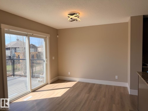 Open concept living space featuring wood-finish flooring, neutral wall tones, and a modern ceiling light fixture - 648 178 Street, Edmonton, AB - Indoor Photo Showing Other Room