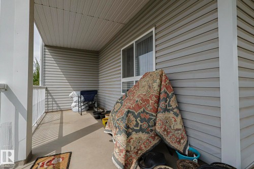 Covered patio featuring concrete flooring, horizontal siding, and a white railing - 314 5340 199 Street, Edmonton, AB - Outdoor With Exterior