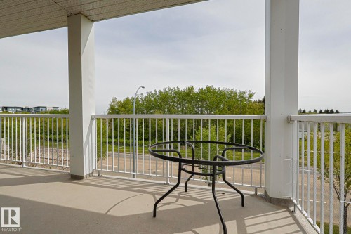 Spacious outdoor balcony featuring a concrete floor, white metal railing, and white support columns - 314 5340 199 Street, Edmonton, AB - Outdoor With Deck Patio Veranda With Exterior