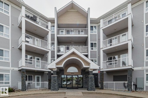 Multi-story building featuring gray horizontal siding and a central gabled entryway - 314 5340 199 Street, Edmonton, AB - Outdoor With Facade