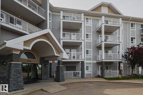 Multi-story residential building featuring a stone-clad entrance with an arched portico and shaker shingle accents - 314 5340 199 Street, Edmonton, AB - Outdoor With Facade
