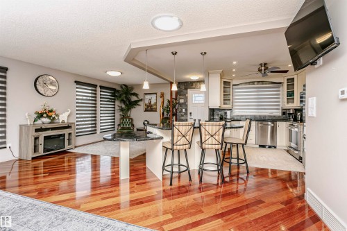 Open concept living area featuring hardwood flooring, recessed lighting, and a kitchen with stainless steel appliances and a breakfast bar - 9831 185 Street, Edmonton, AB - Indoor