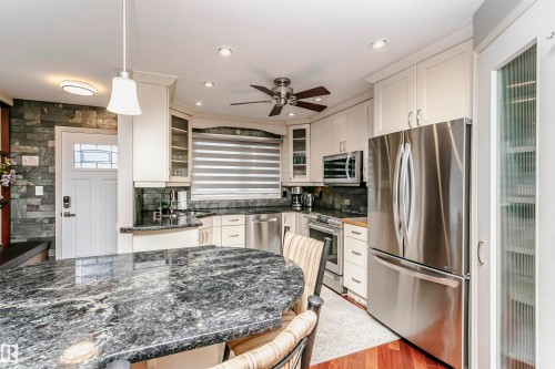 Well-appointed kitchen featuring granite countertops, stainless steel appliances, white cabinetry, and hardwood flooring - 9831 185 Street, Edmonton, AB - Indoor Photo Showing Kitchen With Upgraded Kitchen