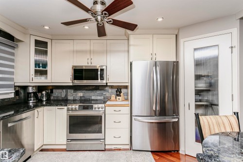 The kitchen features stainless steel appliances, including a microwave, oven, dishwasher, and refrigerator - 9831 185 Street, Edmonton, AB - Indoor Photo Showing Kitchen