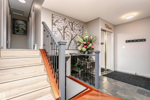 The property features a staircase with light-colored treads and a dark wood handrail, complemented by a balustrade with dark posts and black metal spindles - 9831 185 Street, Edmonton, AB - Indoor Photo Showing Other Room