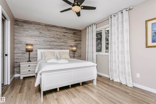 The bedroom features wood-look flooring, a white trim, and a window with white curtains - 9831 185 Street, Edmonton, AB - Indoor Photo Showing Bedroom