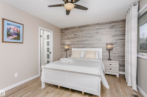 Bedroom featuring wood-look flooring, a ceiling fan with integrated lighting, and a window with patterned curtains - 9831 185 Street, Edmonton, AB - Indoor Photo Showing Bedroom