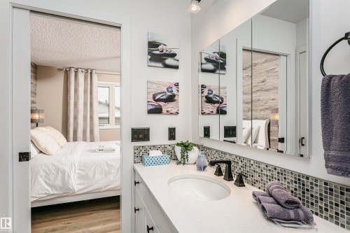 Well-appointed vanity with a rectangular sink, dark fixtures, and a mosaic tile backsplash - 9831 185 Street, Edmonton, AB - Indoor Photo Showing Bathroom