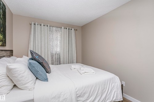 This room features light-colored walls and a window with sheer and opaque curtains - 9831 185 Street, Edmonton, AB - Indoor Photo Showing Bedroom