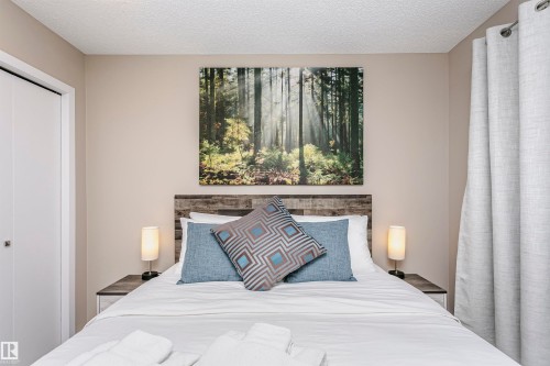 Bedroom featuring a distressed wood style headboard, neutral colored walls, and a large window with privacy curtains - 9831 185 Street, Edmonton, AB - Indoor Photo Showing Bedroom