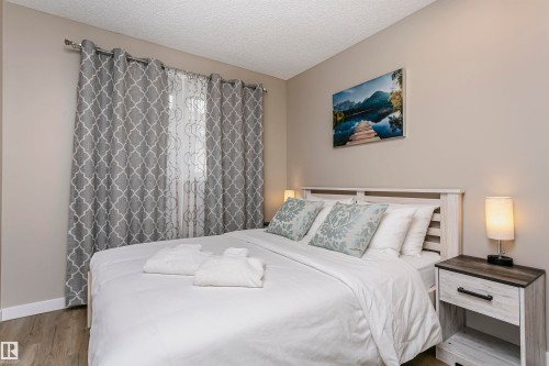 This bedroom features light-toned walls, wood-style flooring, and a bed with a light-colored headboard - 9831 185 Street, Edmonton, AB - Indoor Photo Showing Bedroom