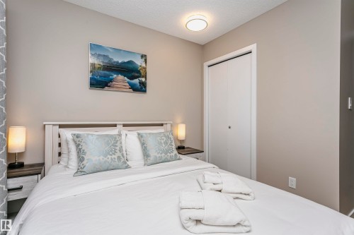 This bedroom features a white bed frame, two nightstands with lamps, and a closet with bifold doors - 9831 185 Street, Edmonton, AB - Indoor Photo Showing Bedroom