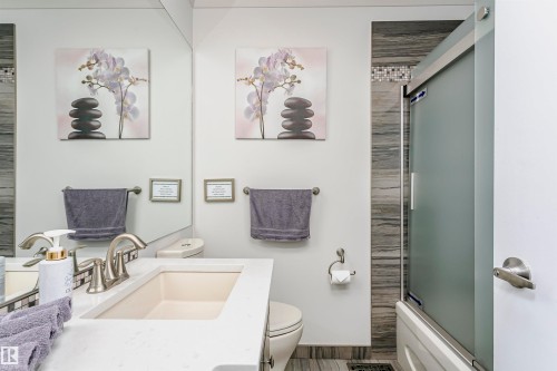 Bathroom featuring a vanity with a white countertop and an integrated sink, a toilet, and a shower with a frosted glass door - 9831 185 Street, Edmonton, AB - Indoor Photo Showing Bathroom