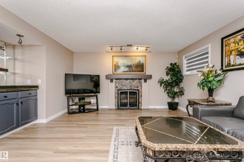 The property features a living area with light-colored flooring and a fireplace with a tiled surround - 9831 185 Street, Edmonton, AB - Indoor Photo Showing Living Room With Fireplace