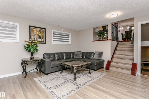 Living area featuring light wood-style flooring, a recessed ceiling light, and a staircase with a wooden handrail - 9831 185 Street, Edmonton, AB - Indoor Photo Showing Living Room
