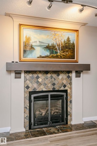 Living area featuring a fireplace with a tiled surround, a dark mantel, and track lighting - 9831 185 Street, Edmonton, AB - Indoor Photo Showing Living Room With Fireplace