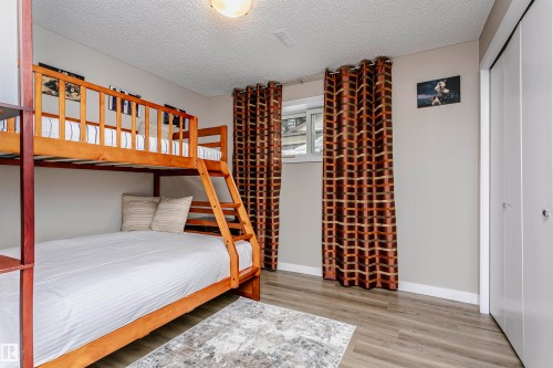 This room features light-colored walls, a window with patterned curtains, and light wood flooring - 9831 185 Street, Edmonton, AB - Indoor Photo Showing Bedroom