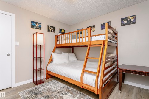 This room features a wooden bunk bed, a floor lamp with shelving, and a desk - 9831 185 Street, Edmonton, AB - Indoor Photo Showing Bedroom