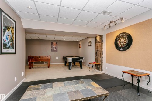 Spacious entertainment area featuring recessed lighting, a dartboard on a cork wall, and a slate tile coffee table - 9831 185 Street, Edmonton, AB - Indoor Photo Showing Other Room