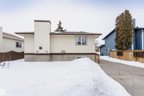 The property features light-colored siding with dark trim, a visible window, and a pathway leading to a wooden fence - 9831 185 Street, Edmonton, AB - Outdoor With Exterior