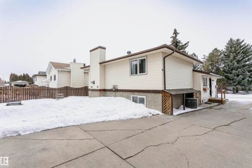 The property features a concrete driveway and a fenced yard with mature trees - 9831 185 Street, Edmonton, AB - Outdoor
