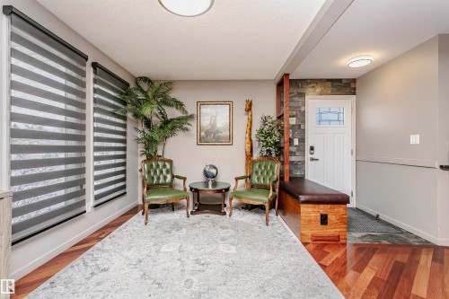 The entrance foyer features hardwood flooring, a contrasting stone accent wall, and a built-in bench with a padded seat - 9831 185 Street, Edmonton, AB - Indoor Photo Showing Other Room