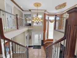 Grand entryway featuring a decorative double-door entry with frosted glass, marble-look tile flooring, and a two-story ceiling - 