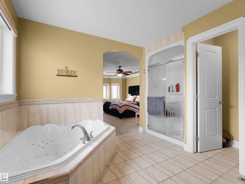 Soaking tub with chrome fixtures, glass-enclosed shower, and tile flooring - 1511 69 Street, Edmonton, AB - Indoor Photo Showing Bathroom