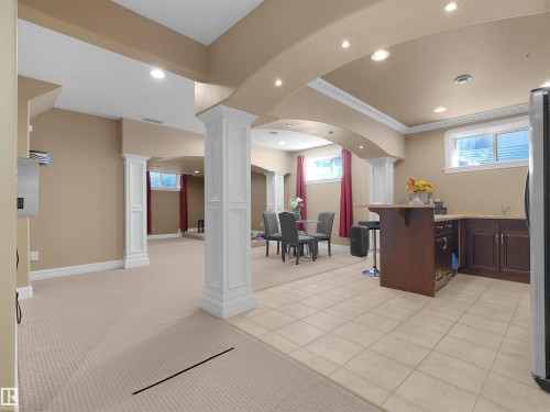 Lower level featuring a compact wet bar with dark wood cabinetry and a light-toned countertop, recessed lighting, decorative crown molding, and a combination of carpet and tile flooring - 1511 69 Street, Edmonton, AB - Indoor Photo Showing Other Room
